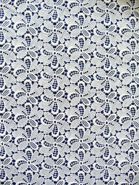 White lace fabric with a flower pattern on a dark blue background. — Stock Photo, Image