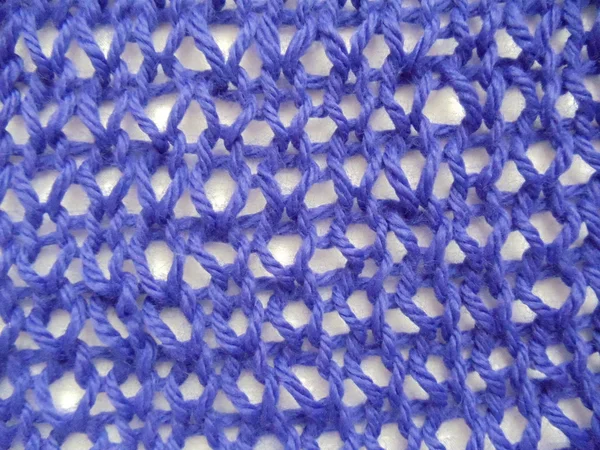 Close-up. A blue handmade knitted woolen fabric with a seamless fishnet pattern on a white background. — Stock Photo, Image