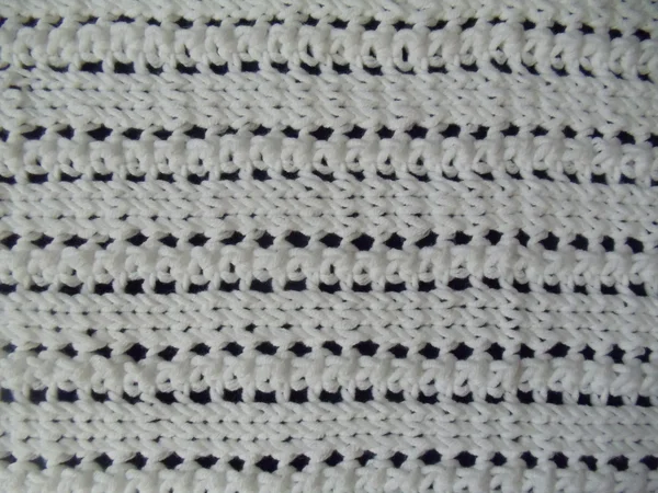 Contexte. Un tissu de coton tricoté à la main blanc avec un motif sans couture sur un fond bleu foncé . — Photo