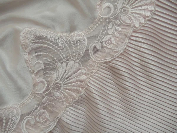 Close-up. een deel van een zachte bleek roze lingerie met kant en accordeon-geplooid weefsel. — Stockfoto