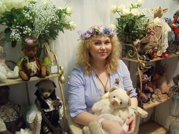 Una bella donna bionda sorridente con una corona di fiori in uno degli stand. Mosca Fiera Internazionale delle Bambole da Collezione e Orsacchiotti. aprile 2013 . — Foto Stock