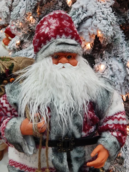 Un juguete Santa Claus con un saco lleno de regalos cerca del árbol de Navidad . —  Fotos de Stock