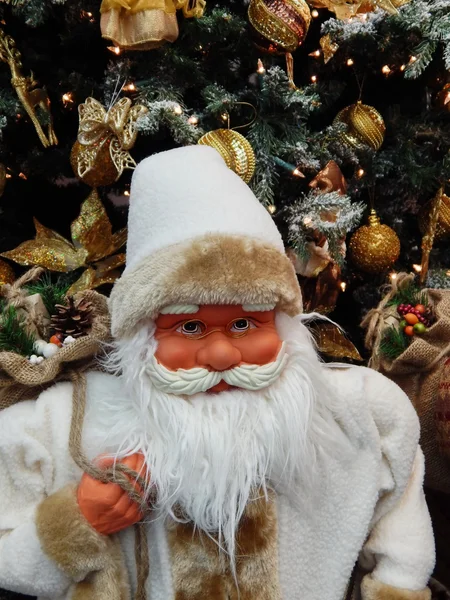 Un juguete Santa Claus con un saco con regalos cerca del árbol de Navidad . — Foto de Stock