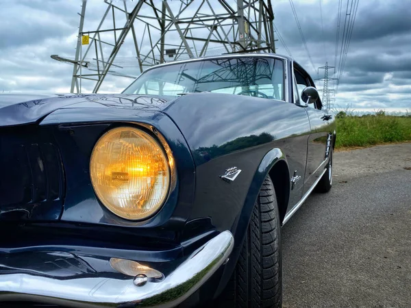Zblízka Světlometu Mustangova Převratu Zaparkovaného Elektrického Sloupu Pod Bouřlivou Oblohou — Stock fotografie