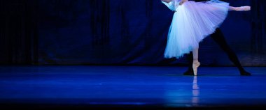 Sahnede yapayalnız dans eden balerinin yakın çekimi. Balerin bacakları yakın plan