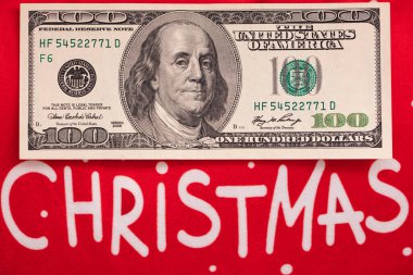 Tasarım amaçlı kırmızı zemin üzerine 100 dolarlık banknot ve Mutlu Noeller metni
