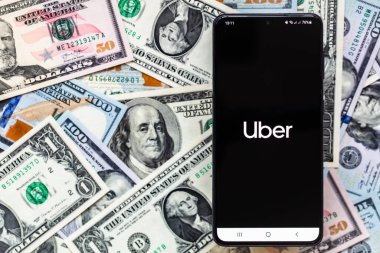 San Francisco, ABD - 1 Aralık 2021: Mobilite hizmeti Uber mobil uygulamalı akıllı telefon ekranı ABD dolar banknotları arka planı