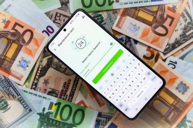 Kyiv, Ukrayna - 1 Aralık 2021: Mobil bankacılık Privat24 başvurusu ile akıllı telefon ekranı ABD doları ve euro banknotları geçmişi
