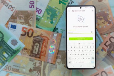 Kyiv, Ukrayna - 1 Aralık 2021: Avro banknotları arka planında mobil bankacılık Privat24 uygulaması olan akıllı telefon ekranı