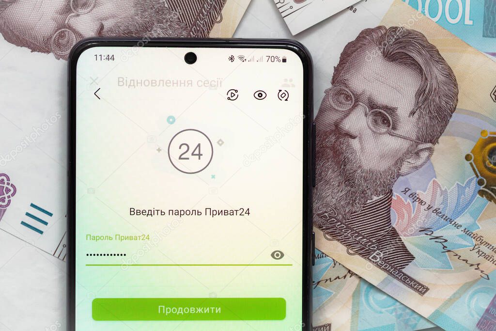 Kyiv, Ukraine - December 1, 2021: smartphone screen with mobile banking Privat24 application on 1000 Ukrainian hryvnia banknotes background