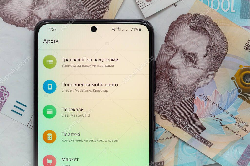 Kyiv, Ukraine - December 1, 2021: smartphone screen with mobile banking Privat24 application on 1000 Ukrainian hryvnia banknotes background