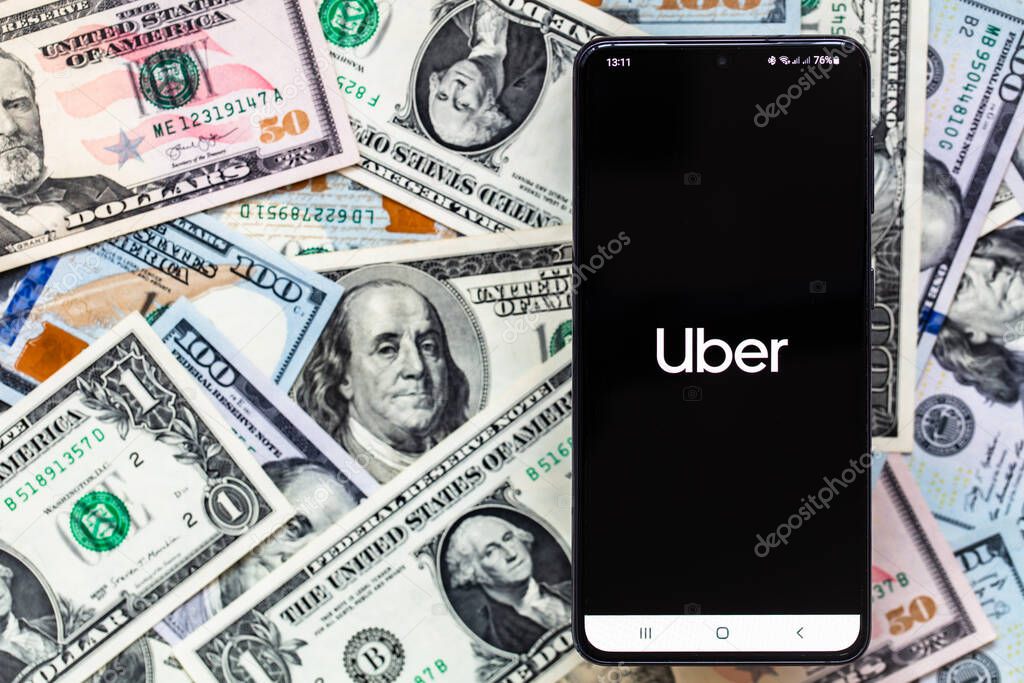 San Francisco, USA - December 1, 2021: smartphone screen with mobility service Uber mobile application on US dollar banknotes background