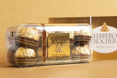 İtalya - 27 Ocak 2022: Altın parıltılı arka planda izole edilmiş Ferrero Rocher premium çikolatası