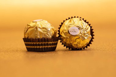 İtalya - 27 Ocak 2022: Altın parıltılı arka planda izole edilmiş Ferrero Rocher premium çikolatası