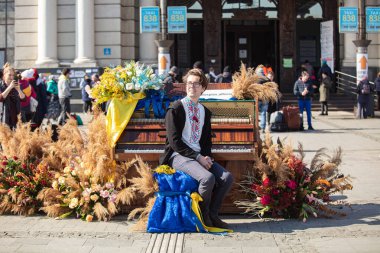 Lviv, Ukrayna - 14 Mart 2022: Rus savaşı sırasında Lviv tren istasyonu yakınlarındaki sokak piyanosunda çalan genç adam