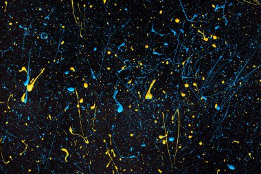 Siyah tuval üzerine mavi ve sarı boya damlaları. Ukrayna bayrağı konsepti .