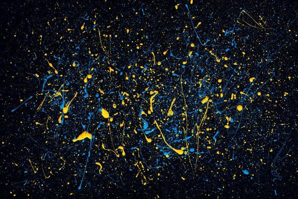 Siyah tuval üzerine mavi ve sarı boya damlaları. Ukrayna bayrağı konsepti .