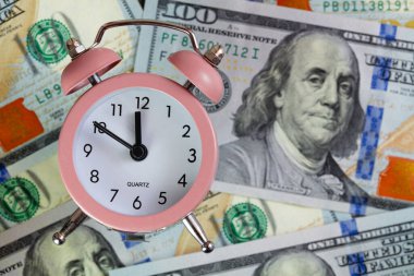 Pembe kuvars alarm saati tasarım amacı için 100 dolarlık bir arkaplanda izole edilmiş.