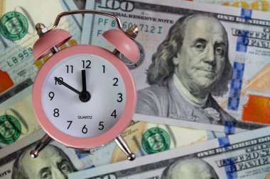 Pembe kuvars alarm saati tasarım amacı için 100 dolarlık bir arkaplanda izole edilmiş.