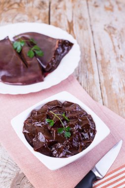 Tahta arka planda beyaz bir tabakta çiğ ciğer. Sığır ciğeri. Çiğ bedeni..