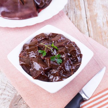 Tahta arka planda beyaz bir tabakta çiğ ciğer. Sığır ciğeri, üst manzara. Çiğ bedeni..