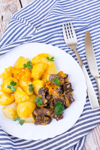 Hígado de carne asada con patatas, cebollas y zanahorias. Delicioso plato de carne. Fotos De Stock