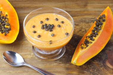 Tropikal meyveli ev yapımı papaya smoothie ve kırsal ahşap masanın üzerinde cam kasede nane şekeri. en üstteki görünüm
