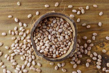 Kaba içinde çiğ karioka çekirdekleri kırsal ahşap masa üzerinde. Brezilya Portekizcesinde ürün adı. Üst görünüm