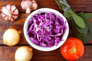 Kırsal ahşap masanın üzerinde seramik kasede dilimlenmiş kırmızı lahana. Üst Görünüm