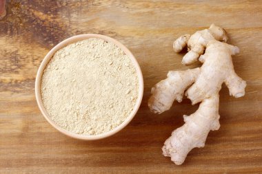 Kırsal ahşap masanın üzerinde seramik kasede zencefil tozu. Antiinflamatuar ve antioksidan.