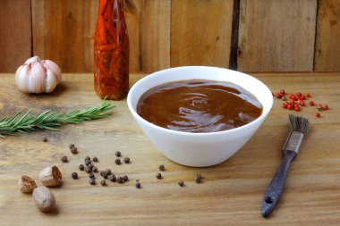 Kasede barbekü sosu ve kırsal ahşap masada fırça. Baharatlar ve bitkiler