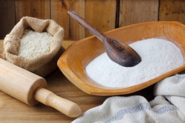 Kırsal ahşap masanın üzerinde, kasede çiğ organik pirinç unu. Glütensiz yemek.