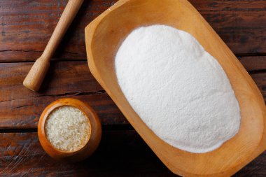 Kırsal ahşap masanın üzerinde, kasede çiğ organik pirinç unu. Glütensiz yemek.