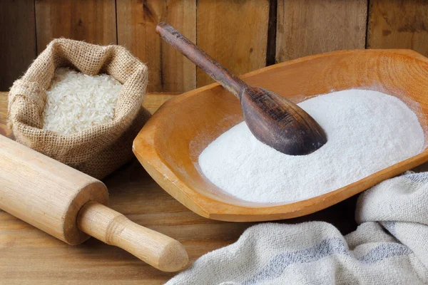 Kırsal ahşap masanın üzerinde, kasede çiğ organik pirinç unu. Glütensiz yemek.