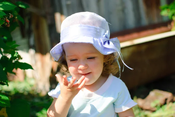 The child eats berries in a garden — Stock Photo, Image