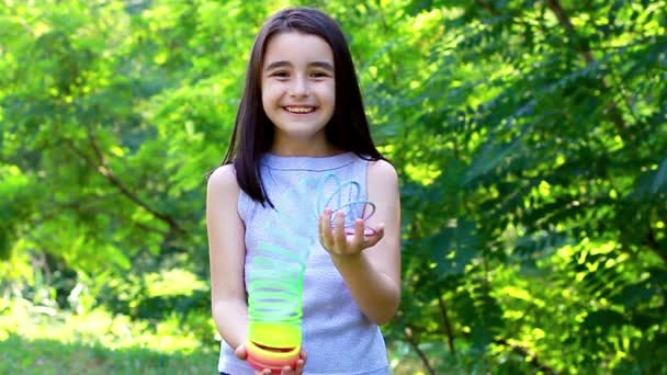 Belle petite fille jouant avec un jouet de printemps en plastique coloré — Video