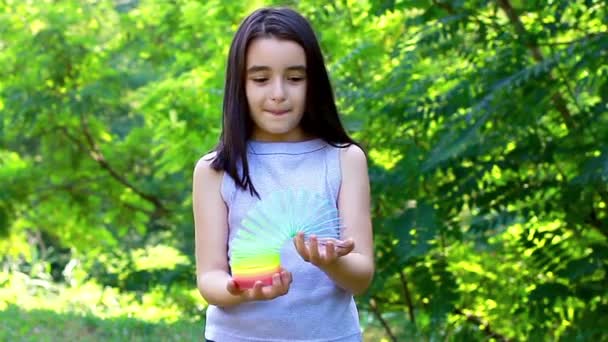 Menina bonita brincando com brinquedo colorido mola de plástico — Vídeo de Stock