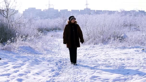 Senior vrouw lopen op de weg in de winter — Stockvideo