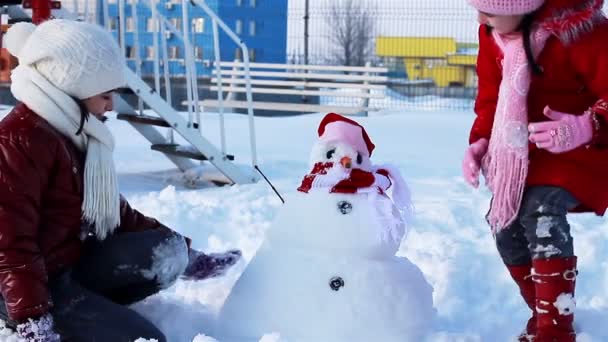 Happy girls with snowman — Stock Video