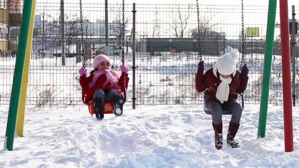 Girls in swings in winter playground — Wideo stockowe