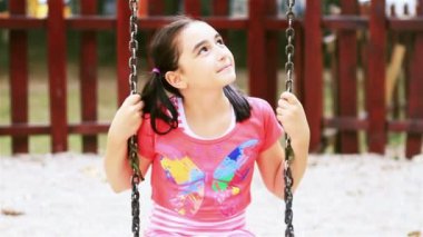 küçük kız kameraya gülümseyen salıncak üzerinde