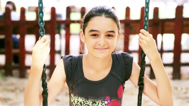 Девочка-подросток на качелях улыбается в камеру — стоковое видео