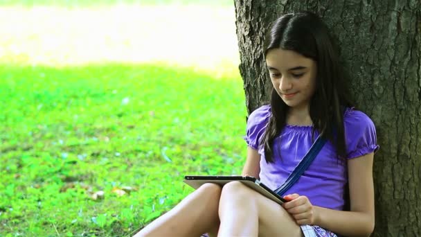 Adolescente usando tablet digital no parque — Vídeo de Stock