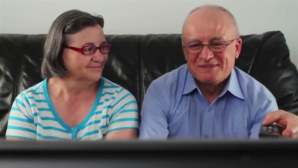 Onnellinen vanhempi pari katsomassa televisiota yhdessä — kuvapankkivideo