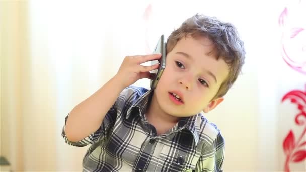 Улыбающийся мальчик разговаривает по смартфону — стоковое видео