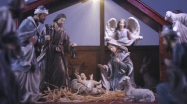 Yüce İsa 'nın doğuş sahnesinde heykelcikler durağan ve ışık parçacıklarıyla. Meryem ve Yusuf 'la birlikte bir ahırda İsa' nın doğumu. Noel sahnesi. Dolly 4K çekti.