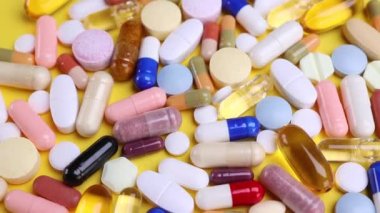 Sarı arka planda farklı haplar. İlaçlar, haplar, antibiyotikler, vitaminler, sağlık hizmetleri, ilaç endüstrisi, uyuşturucu kullanımı, ilaç konsepti. Dolly 4K çekti.