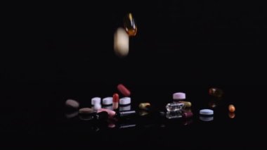 Siyah arka plana düşen farklı haplar. İlaçlar, haplar, antibiyotikler, vitaminler, sağlık hizmetleri, ilaç endüstrisi, uyuşturucu kullanımı, ilaç konsepti. Yavaş çekim