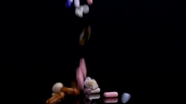 Siyah arka plana düşen farklı haplar. İlaçlar, haplar, antibiyotikler, vitaminler, sağlık hizmetleri, ilaç endüstrisi, uyuşturucu kullanımı, ilaç konsepti. Yavaş çekim