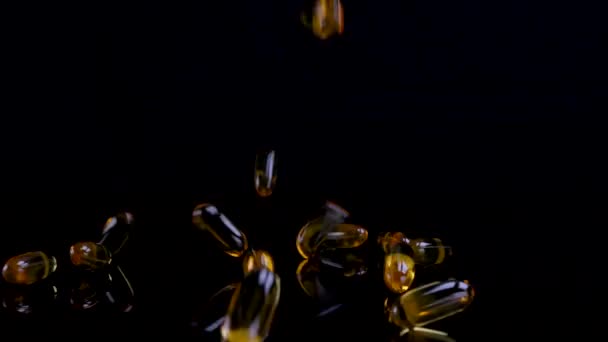 欧米茄鱼油营养补充剂落在光滑的黑色背景上 欧米茄鱼油软化饮食补充剂背景 健康生活和心脏健康概念 — 图库视频影像